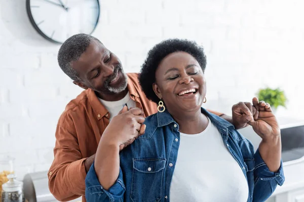 Feliz adulto mayor afroamericano hombre cogido de la mano de la esposa sonriente con los ojos cerrados - foto de stock