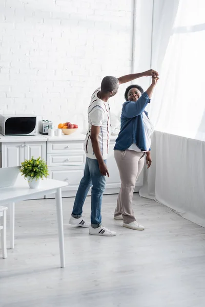 Full length of happy senior african american couple dancing in kitchen — Stock Photo