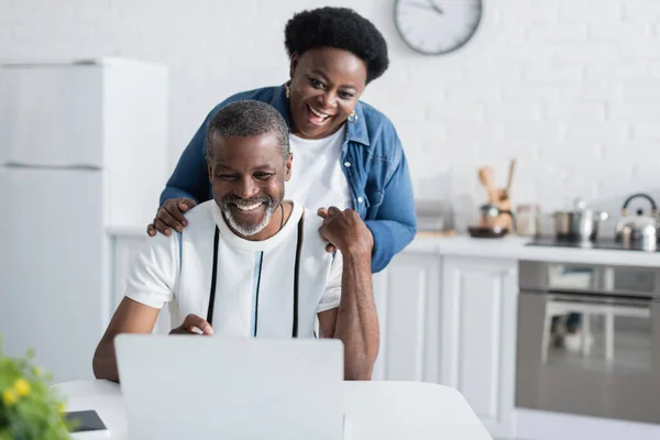 Happy african american man and woman looking at laptop — Stock Photo