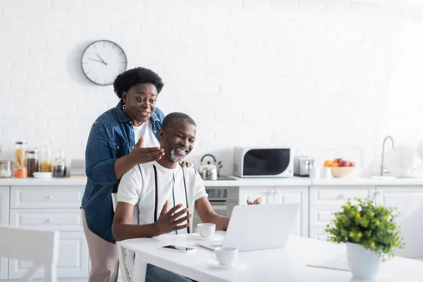 Homem americano africano feliz e mulher olhando para laptop durante chamada de vídeo — Fotografia de Stock