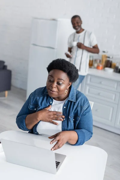 Senior african american woman talking during video call near blurred husband — Stock Photo