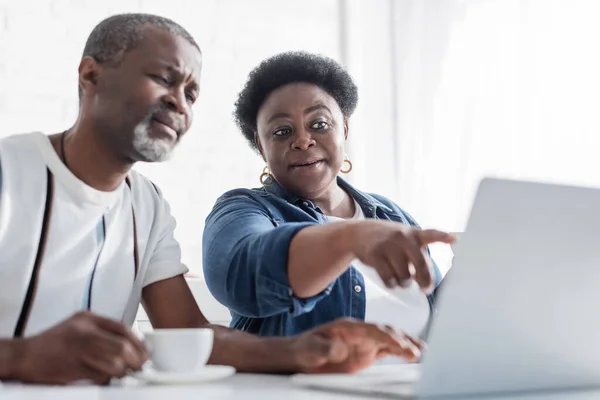 Aposentado Africano americano mulher apontando para laptop perto do marido — Fotografia de Stock