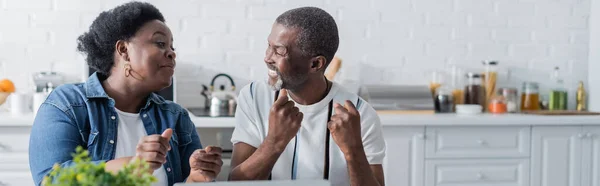 Marido y esposa afroamericanos mayores regocijándose en la cocina, pancarta - foto de stock