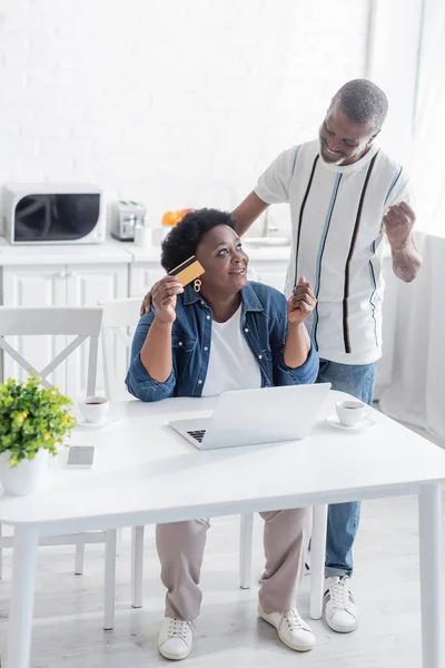 Feliz pareja afroamericana senior haciendo pedido en línea mientras usa el ordenador portátil - foto de stock