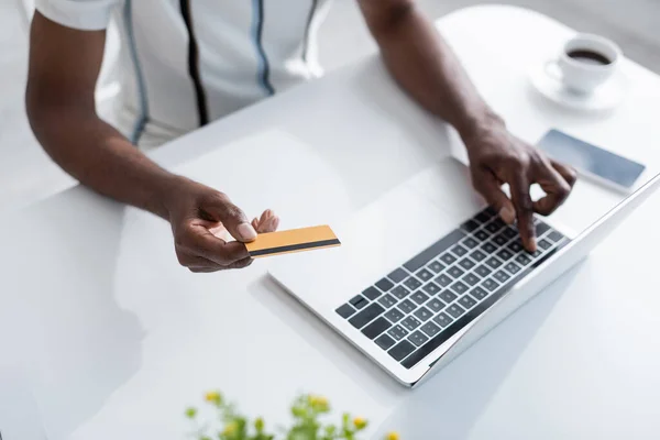 Cropped view of senior african american man holding credit card near laptop while shopping online — Stock Photo