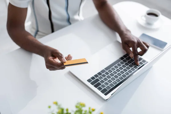 Vista ritagliata di anziano uomo africano americano in possesso di carta di credito vicino al computer portatile durante lo shopping online — Foto stock