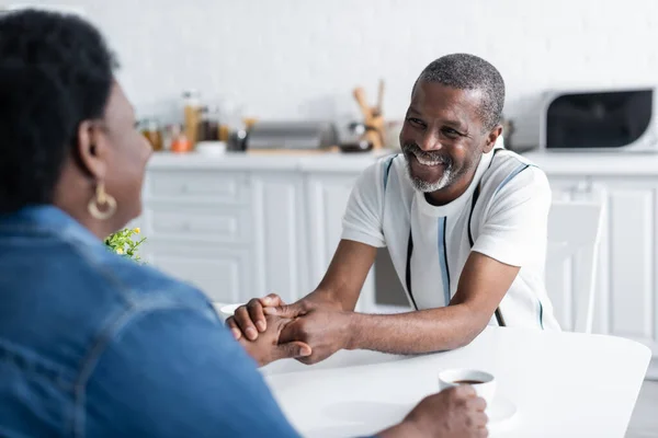 Homme afro-américain senior souriant et se tenant la main avec sa femme — Photo de stock