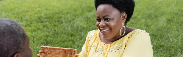 Feliz africano americano mujer sonriendo cerca marido, bandera - foto de stock