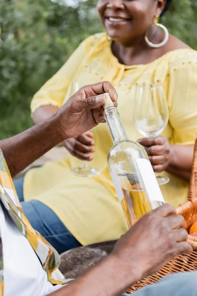 Обрізаний вид на старшого афроамериканця, що тримає пляшку вина біля щасливої дружини — стокове фото