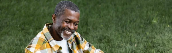 Feliz sénior afroamericano hombre sonriendo en parque, pancarta - foto de stock