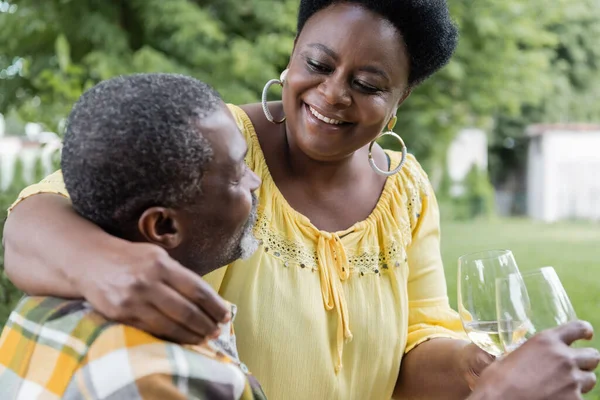 Feliz y sénior africano americano pareja tintineo vasos de vino - foto de stock