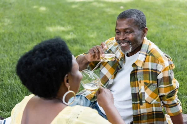 Happy and senior african american couple drinking wine during picnic — Stock Photo