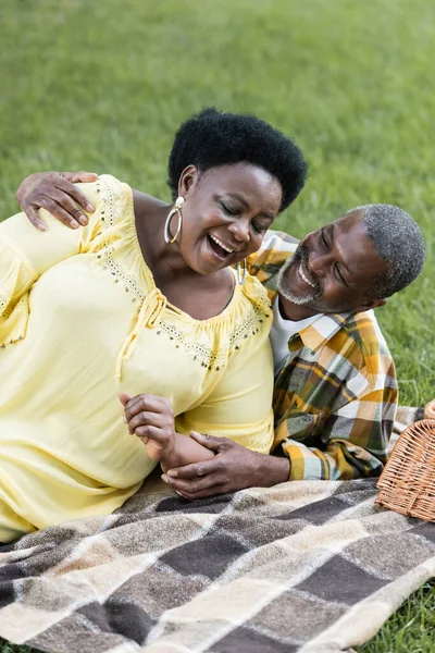 Smiling and senior african american couple lying on blanket during picnic — Stock Photo