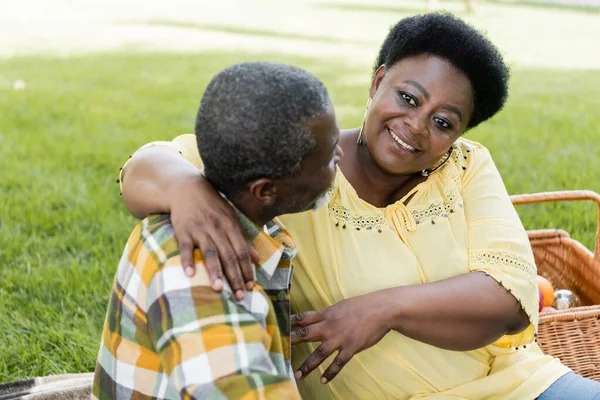 Senior africano americano pareja abrazando y sonriendo en parque - foto de stock