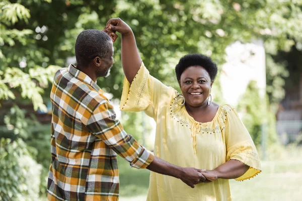 Senior african american couple dancing and smiling in park — Stock Photo