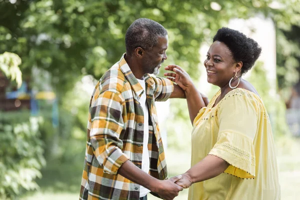 Feliz adulto mayor afroamericano pareja bailando en parque - foto de stock