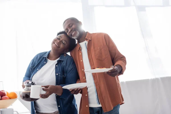 Cheerful and senior african american woman holding breakfast and leaning on each other — Stock Photo