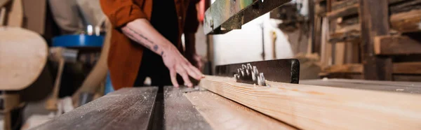 Surface level of workbench with circular saw and plank near cropped carpenter, banner — Stock Photo