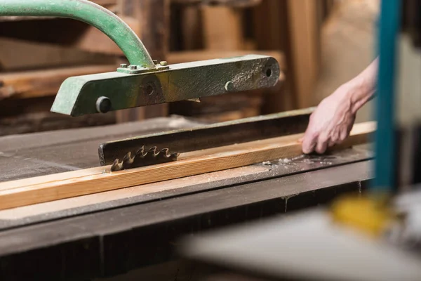 Partial view of carpenter working on circular saw on blurred foreground — Stock Photo