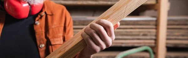 Partial view of furniture designer holding plank in carpentry workshop, banner — Stock Photo