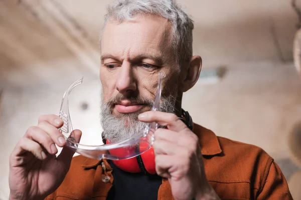 Bearded middle aged furniture designer holding goggles in workshop — Stock Photo