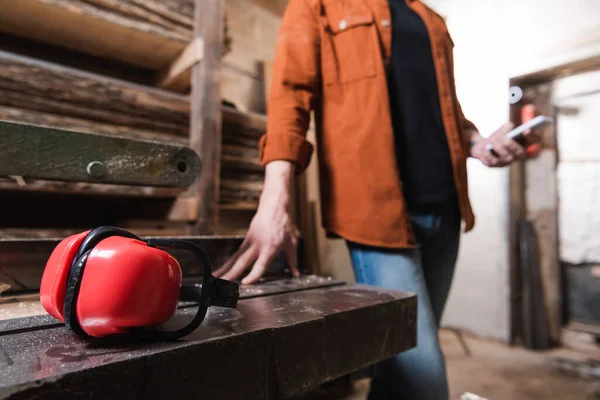 Selektiver Fokus von schützenden Ohrenschützern in der Nähe zugeschnittener Möbeldesigner auf verschwommenem Hintergrund — Stockfoto