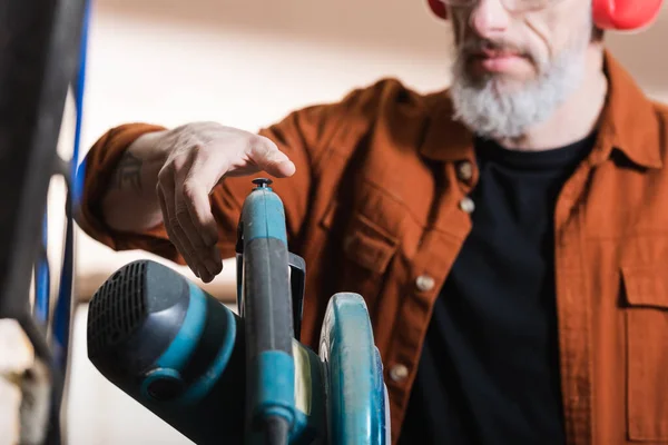 Partial view of bearded joiner near miter saw in woodwork studio — Stock Photo