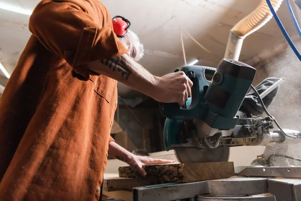 Low angle view of woodworker cutting board with miter saw — Stock Photo