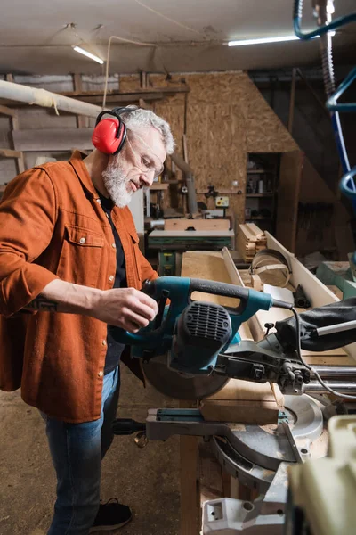 Bärtige Holzschneidebretter mit Gehrungssäge in der Werkstatt — Stockfoto