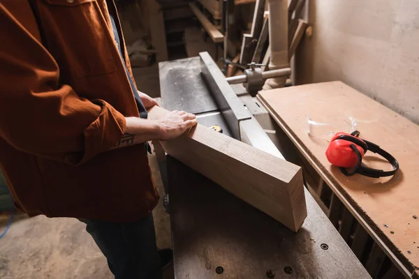 Vista cortada de madeira segurando placa perto da máquina jointer — Fotografia de Stock