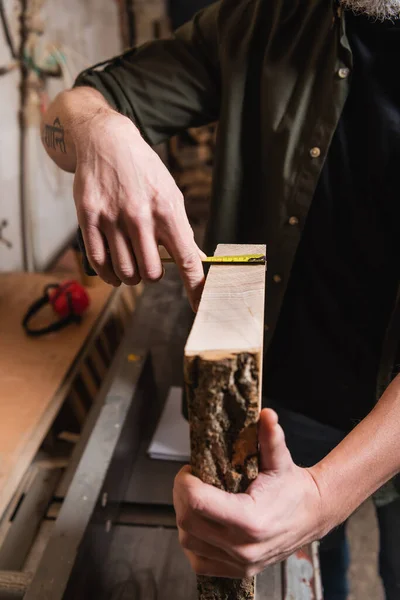 Cropped view of carpenter measuring board in woodwork atelier — Stock Photo