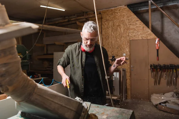 Mature grey haired carpenter in goggles working near ventilation hood — Stock Photo