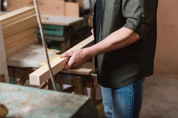 Vue recadrée du designer de meubles tenant des planches dans un atelier de menuiserie — Photo de stock