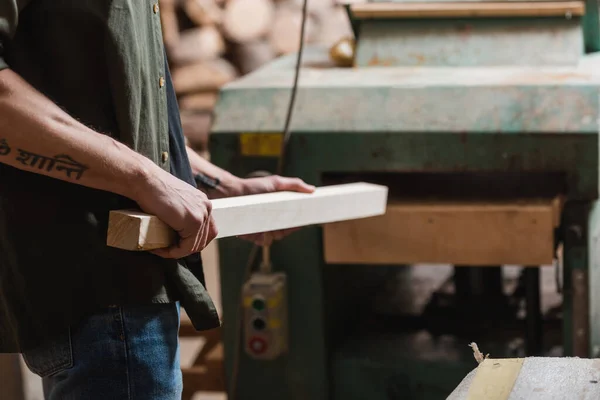 Ausgeschnittene Ansicht eines Tischlers mit Planke bei der Arbeit an einem Werkzeug in der Werkstatt — Stockfoto