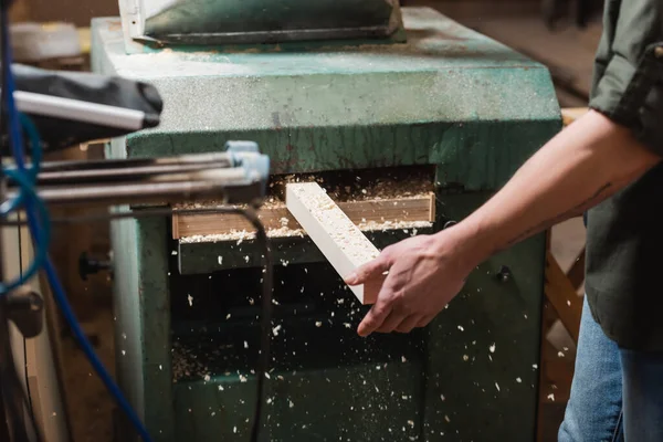 Partial view of woodworker sawing plank in thickness planer — Stock Photo