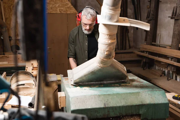 Bearded carpenter working near ventilation hood on blurred foreground — Stock Photo