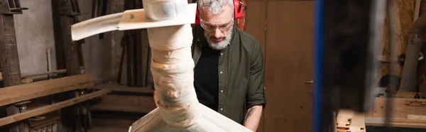 Bearded carpenter in goggles working near blurred ventilation hood, banner — Stock Photo