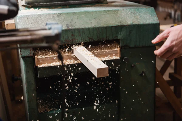 Plank and sawdust near thickness planer and cropped carpenter in workshop — Stock Photo