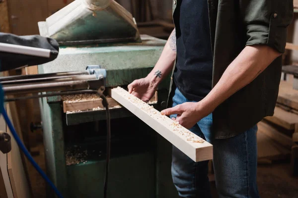 Cropped view of furniture designer sawing wooden plank in thickness planner — Stock Photo