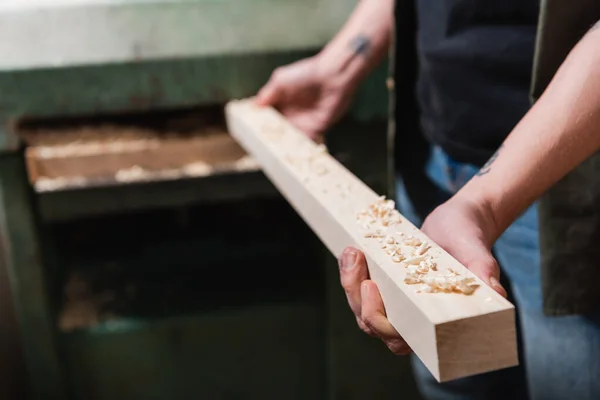 Cropped view of woodworker holding board near blurred thickness planner — Stock Photo