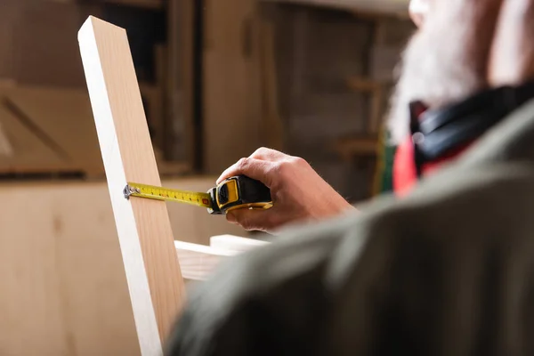 Vista ritagliata di mobili sfocati designer misurazione tavola di legno con metro a nastro — Foto stock