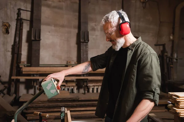 Side view of middle aged woodworker pushing button on control relay in workshop — Stock Photo