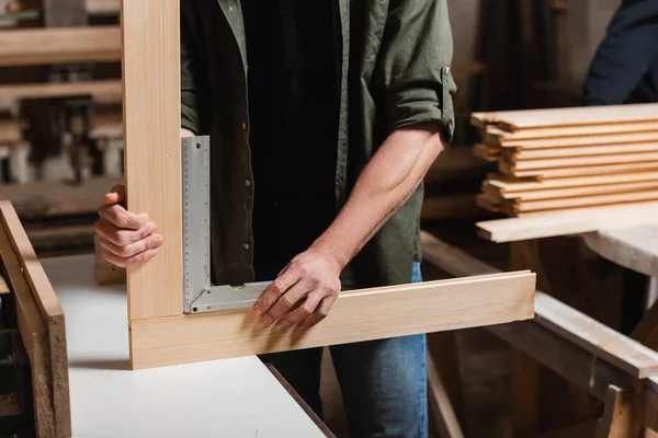 Cropped view of furniture designer measuring wooden details with corner ruler — Stock Photo