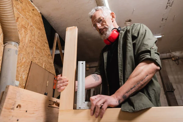 Vue à angle bas du concepteur de meubles mesurant les détails en bois dans le studio de menuiserie — Photo de stock