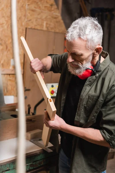 Bearded carpenter connecting wooden details in woodwork studio — Stock Photo