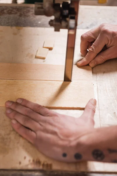 Cropped view of joiner cutting plywood with band saw — Stock Photo