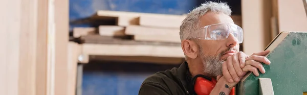 Designer de meubles aux cheveux gris coûteux dans des lunettes détournant les yeux dans l'atelier, bannière — Photo de stock