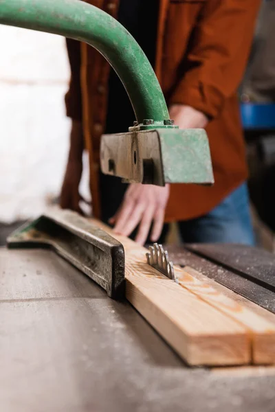 Cropped view of carpenter cutting board on circular saw in woodwork studio — Stock Photo