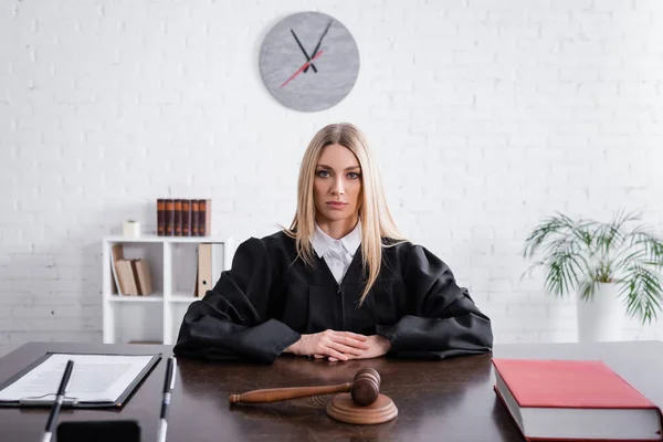Blonde prosecutor in mantle sitting at desk near gavel and lawsuit — Stock Photo