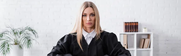 Blonde prosecutor in black mantle looking at camera, banner — Stock Photo